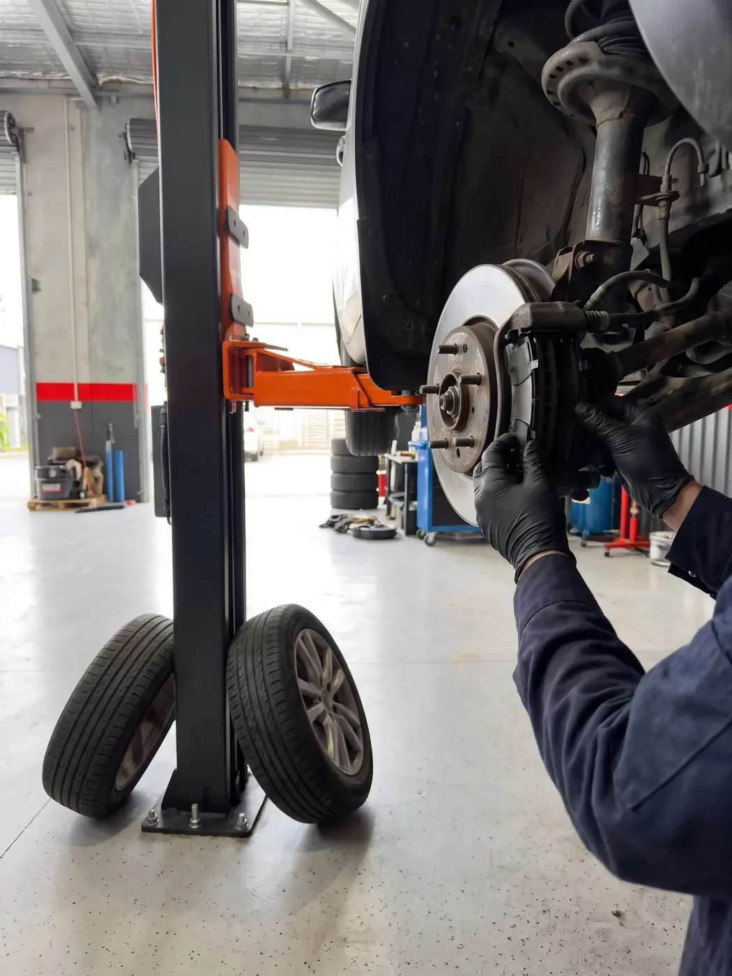 Mechanic working on a brake rotor with the car raised on a hoist