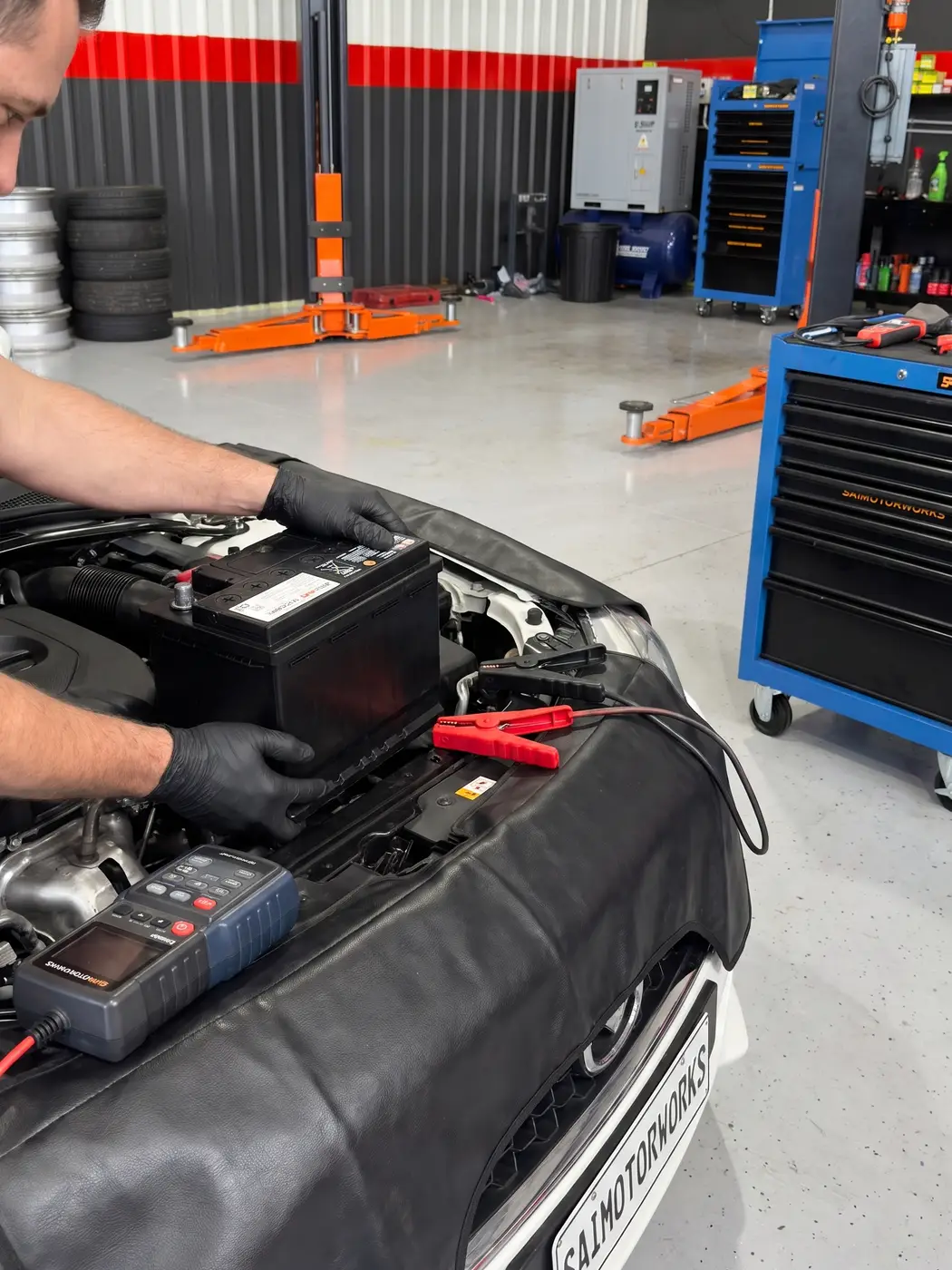 Mechanic testing a car battery in the engine bay